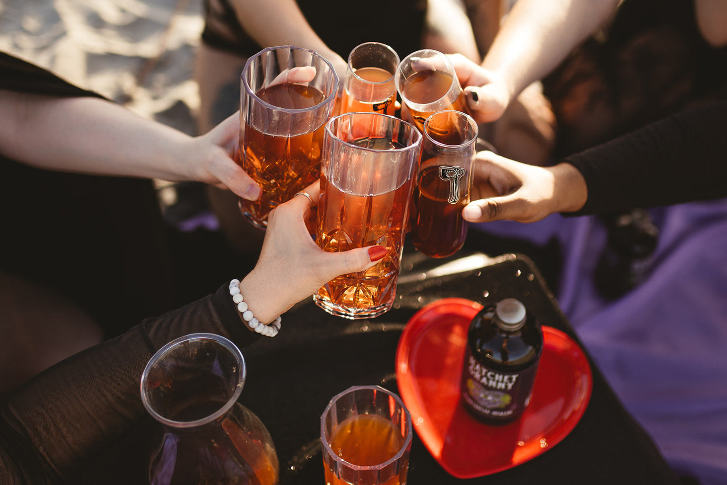 Friends raising glasses of Heartbreak Healer at sunset on the beach